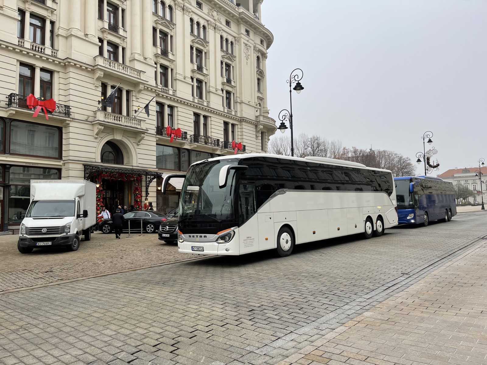 Zdjęcie przedstawia wynajęty biały autokar w drodze na lotnisko Chopina w Warszawie